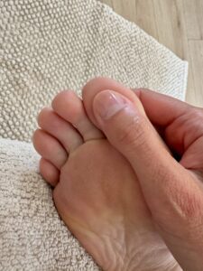 Stimulation en réflexologie plantaire du point du cerveau, au niveau du gros orteil, pour favoriser la détente et améliorer le sommeil naturellement.